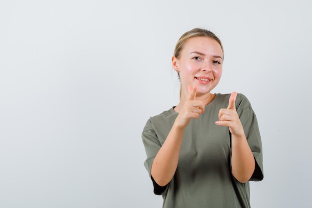 De lachende vrouw wijst naar de camera met wijsvingers op een witte achtergrond