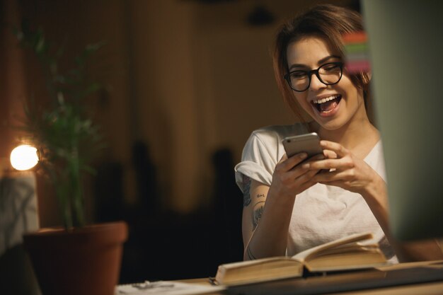 De lachende zitting van de dameontwerper binnenshuis bij nacht het babbelen