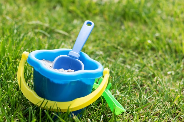 De lepel van stuk speelgoed kinderen in een emmer op het gras