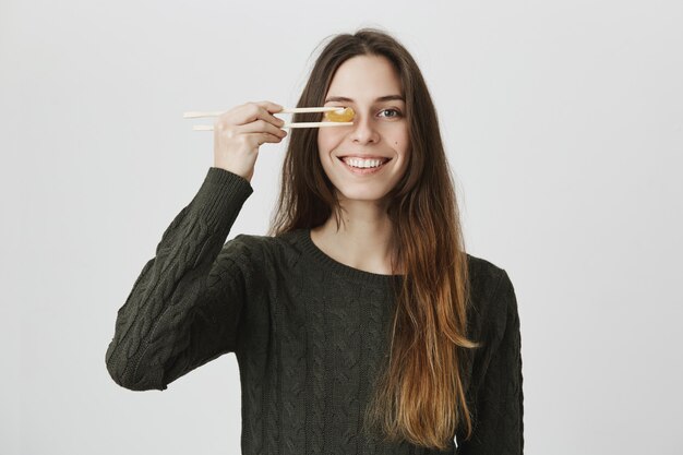 De leuke het glimlachen mandarijn van de vrouwenholding met eetstokjes over oog