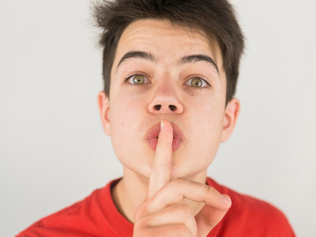 De leuke jonge jongen in rode t-shirt houdt stil teken