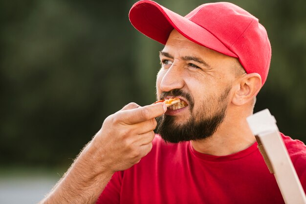 De leveringskerel die van de close-up pizza eet