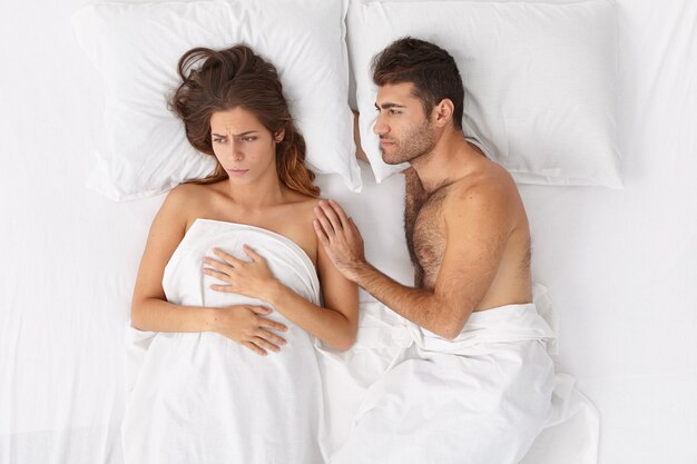 De liefhebbende echtgenoot probeert de vrouw die wat problemen heeft te steunen en te kalmeren, samen in bed te blijven onder wit beddengoed, negatieve emoties te uiten. Familieproblemen, relatie en stressvolle situatie