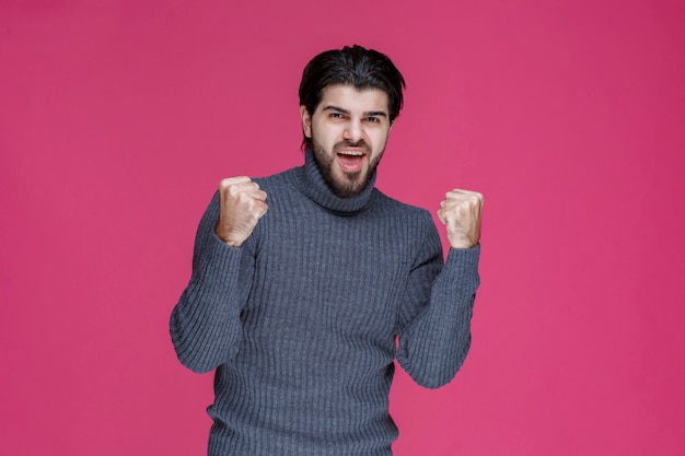 De man in een grijs overhemd ziet er zelfverzekerd uit.