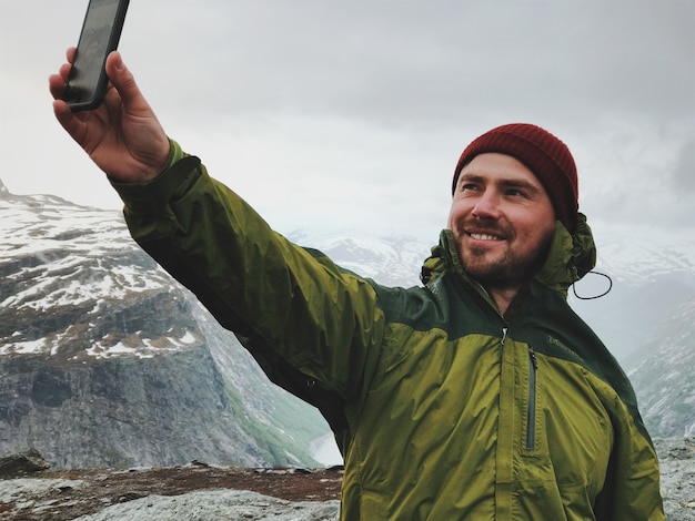 Gratis foto de man neemt een selfie in de voorkant van de bergen