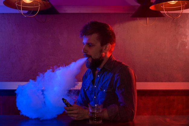 De man rookt een elektronische sigaret bij de vape-winkel. Vape-bar.