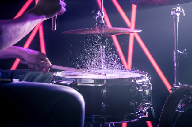 De man speelt drums, op de achtergrond van gekleurde lichten