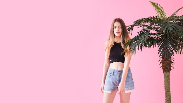 Gratis foto de manierconcept van de zomer met jonge vrouw naast palm