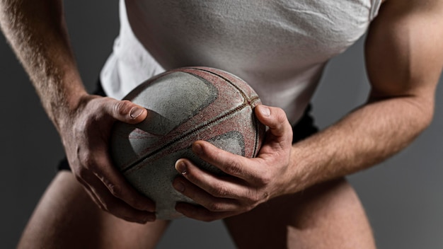 De mannelijke bal van de rugbyspelerholding met beide handen