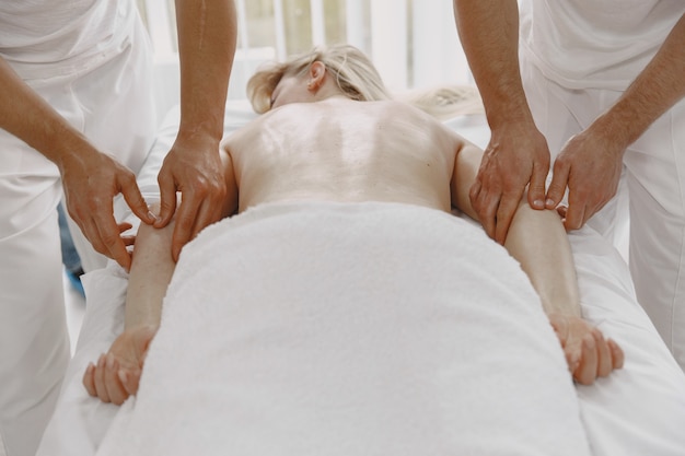 De massage met vier handen. Concept van gezondheidszorg en vrouwelijke schoonheid. Twee masseuses maken een dubbele massage van een meisje. Vrouw in een kuuroordsalon.