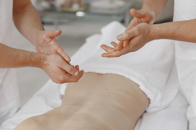 De massage met vier handen. Concept van gezondheidszorg en vrouwelijke schoonheid. Twee masseuses maken een dubbele massage van een meisje. Vrouw in een kuuroordsalon.