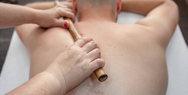 De masseur masseert bamboestokken tijdens de behandeling.