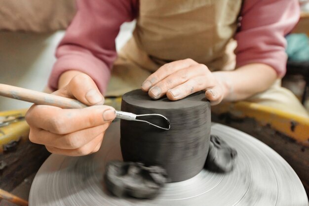 De meester van het beeldhouwen van aardewerk werkt in een atelier en vormt de klei