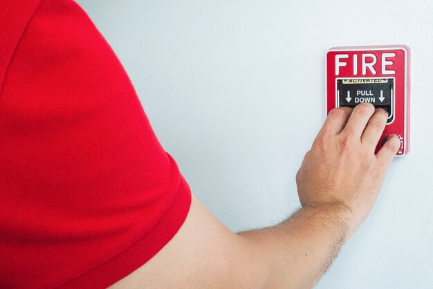 De mens bereikt zijn hand om brandalarmhandstation te duwen