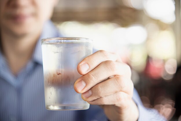 De mens drinkt vers koud zuiver water in glas