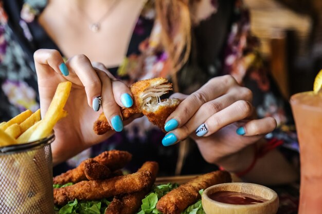 De mens eet kippenvingers met het zijaanzicht van de frietenketchup