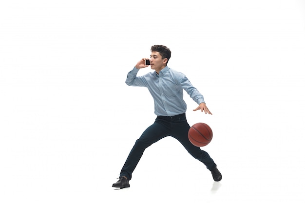 De mens in bureau kleedt het spelen van basketbal op witte ruimte. Ongewone look voor zakenman in beweging, actie. Sport, gezonde levensstijl.