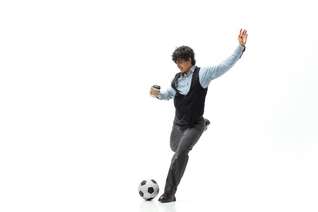 De mens in bureaukleren die voetbal of voetbal met bal op witte ruimte spelen. Ongewone look voor zakenman in beweging, actie. Sport, gezonde levensstijl.