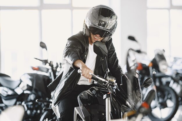 De mens koos voor motorfietsen in de moto-winkel. Man in een zwart jasje. Man in een helm.