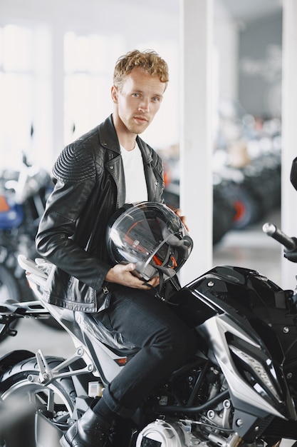 De mens koos voor motorfietsen in de moto-winkel. Man in een zwart jasje. Man in een helm.