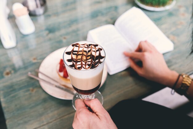 De mens leest met het dessert van het koffie latte melkschuim