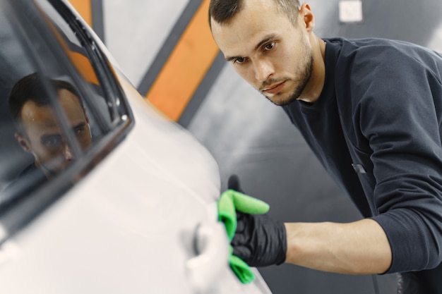 De mens poetst een auto in een garage op