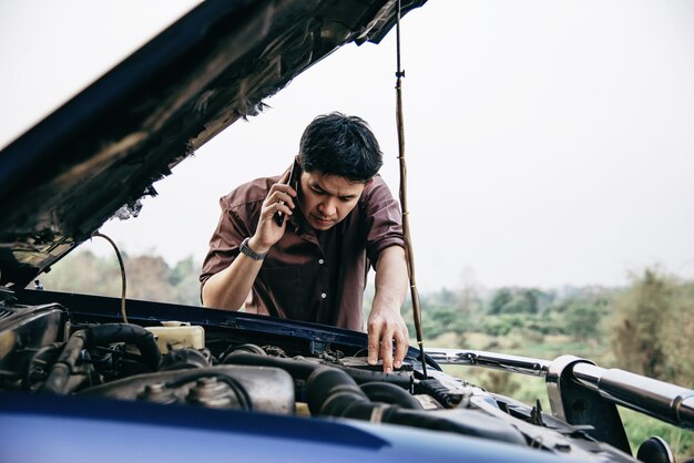 De mens probeert een motor van een motorprobleem op een lokale weg te bevestigen