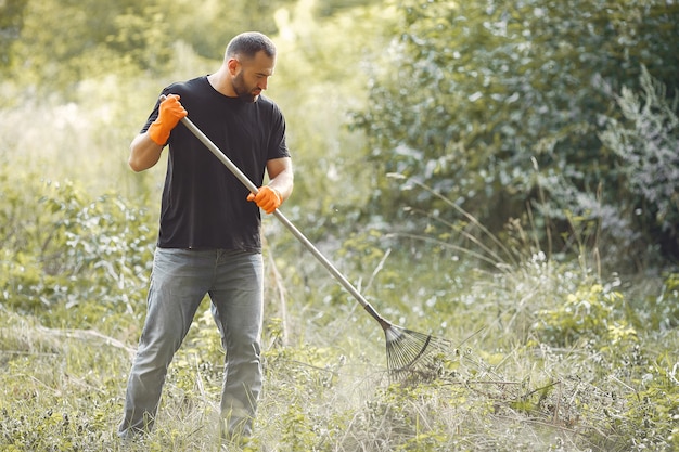 De mens verzamelt bladeren en maakt het park schoon