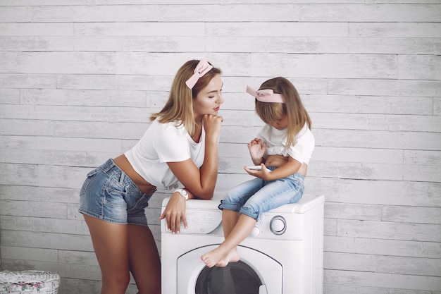 De moeder en de dochter in een badkamers wassen dichtbij mashine