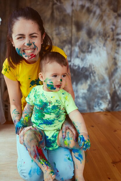 De moeder en zoon schilderen een groot papier met hun handen