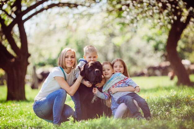 De moeder, kinderen en hond zittend op het gras