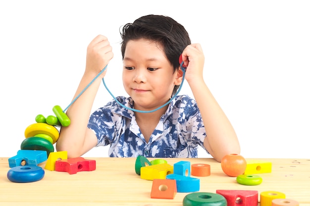 De mooie Aziatische jongen is speel kleurrijk houtsnedestuk speelgoed