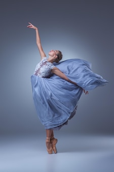 De mooie ballerina die danst in blauwe lange jurk