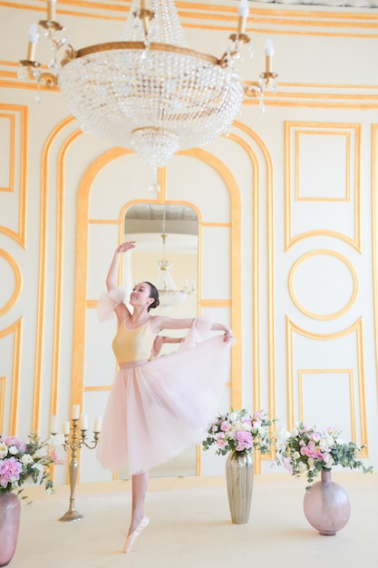 De mooie ballerina in roze kleren stelt in een luxeruimte