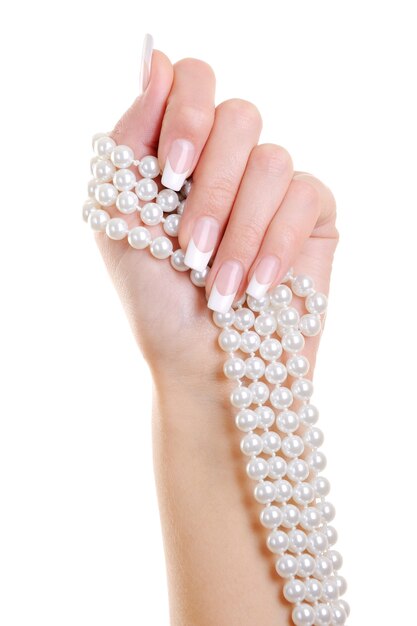 De mooie elegante vrouwenhand met Franse manicure houdt de witte perl over