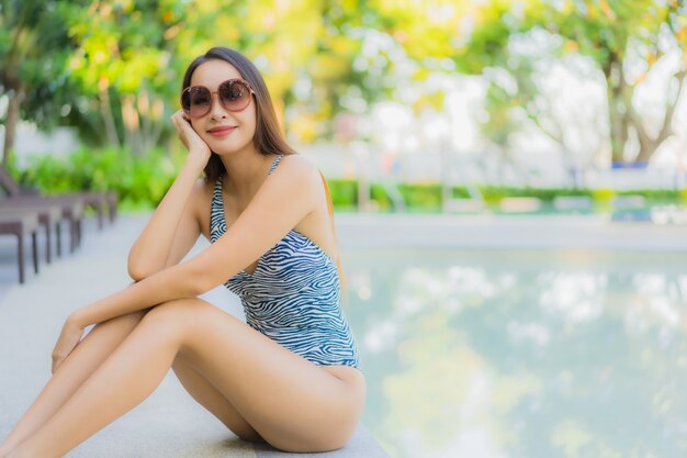 De mooie jonge Aziatische vrouwen gelukkige glimlach ontspant rond openluchtzwembad in hoteltoevlucht