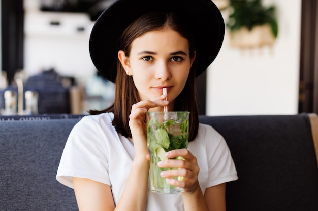 De mooie jonge vrouw drinkt limonade in koffie