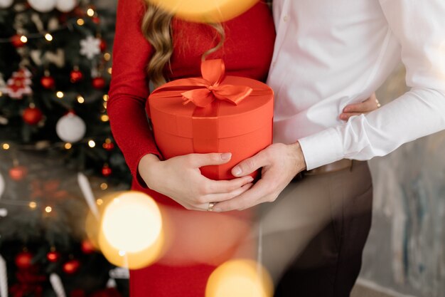 De mooie man en de vrouw in fancy sluiten stellen vóór rijk verfraaide Kerstboom en ruilen hun