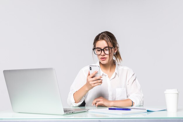 De mooie telefoon van de bedrijfsvrouwenholding met de computer op kantoor dat op witte achtergrond wordt geïsoleerd