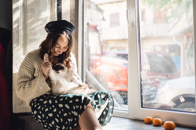 Gratis foto de mooie vrouw die haar kat houdt handtastelijk wordt zich uitrekt