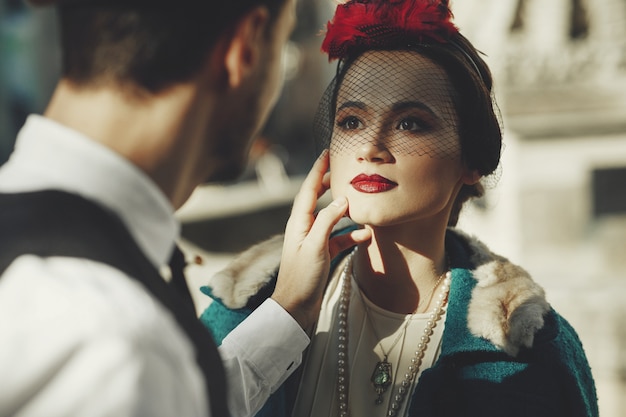 De mooie vrouw gekleed in jaren &#39;30stijl bevindt zich op de straat en bekijkt haar man met liefde
