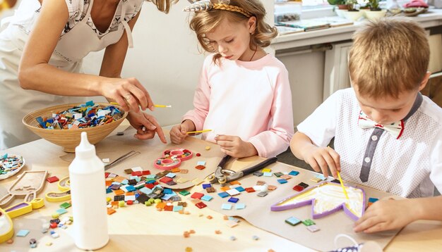 De mozaïekpuzzelkunst voor kinderen, creatief spel voor kinderen. De handen spelen mozaïek aan tafel. Close-up van kleurrijke veelkleurige details. Creativiteit, ontwikkeling van kinderen en leerconcept