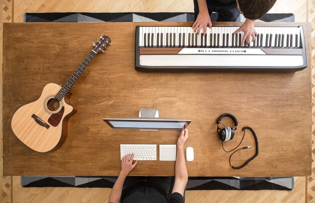 De muzikanten maken muziek in zijn studio door keyboards te bespelen. De procesopname van geluid.