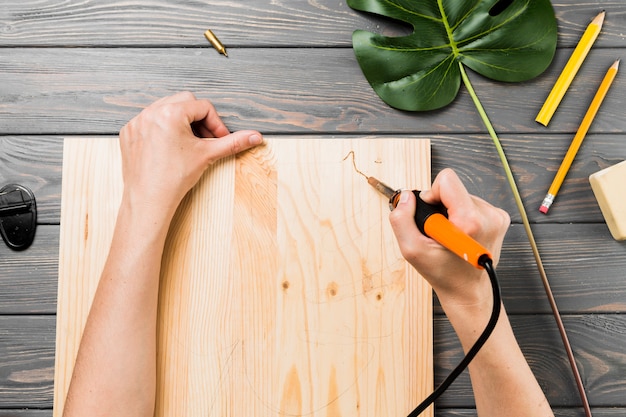 Gratis foto de opgeheven mening van hand snijdt harde houten raad op bureau