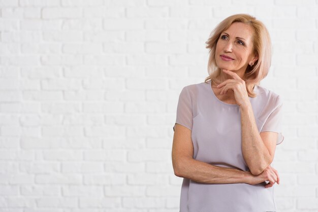 De oude dame die van Smiley weg met baksteenachtergrond kijkt