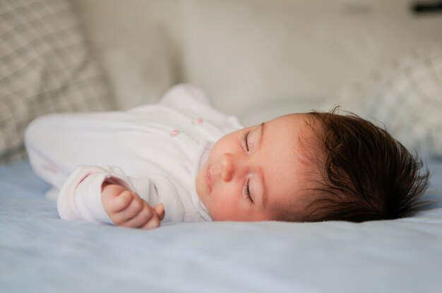 De pasgeboren slaap van het babymeisje op blauwe bladen thuis