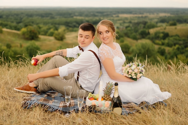De pasgetrouwden op picknick in de natuur. bruid en bruidegom na huwelijksceremonie.