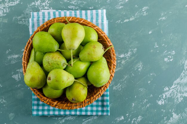 De peren in een mandvlakte leggen op pleister en keukenhanddoekachtergrond