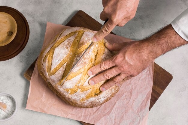 De persoon die de helft van brood plat snijdt lag