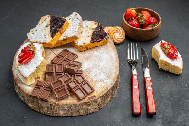 De plakjes van de vooraanzichtcake met chocostaven en aardbeien op grijze achtergrond